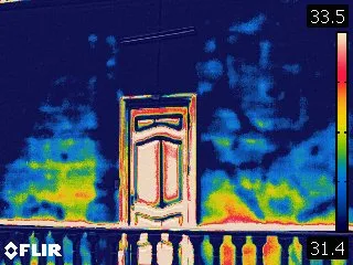 Termografía IR — fachada con puerta, gradiente azul-amarillo revela humedad capilar — Casa Riva Agüero Lima
