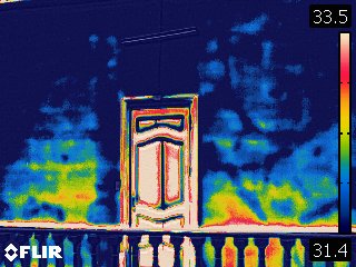 Termografía IR — fachada con puerta, gradiente azul-amarillo revela humedad capilar — Casa Riva Agüero Lima